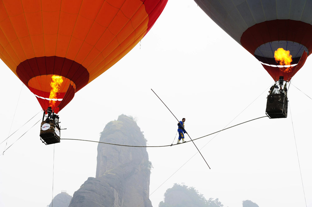 wire cyclist suspended between two hot air balloons